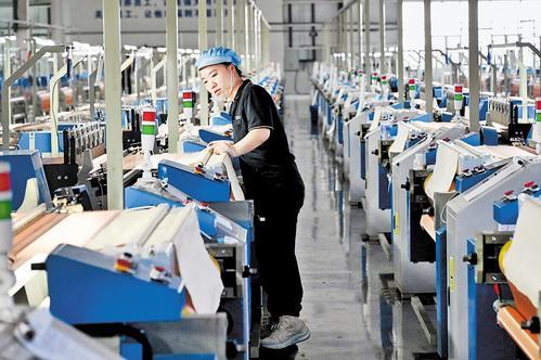 12月10日,安平县赛航丝网制造有限公司工人在生产车间查看智能化织网机运行情况。 本报记者焦磊摄