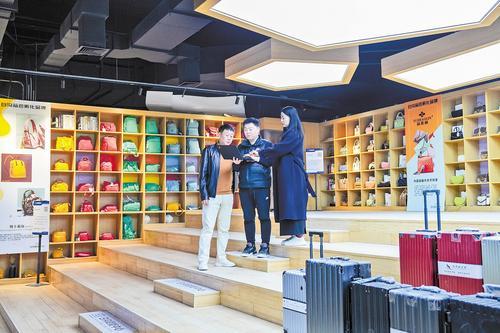 11月27日,白沟箱包数字化转型赋能中心工作人员(左二)向商户展示通过共享设计平台生成的效果图。本报记者 许佳奇摄