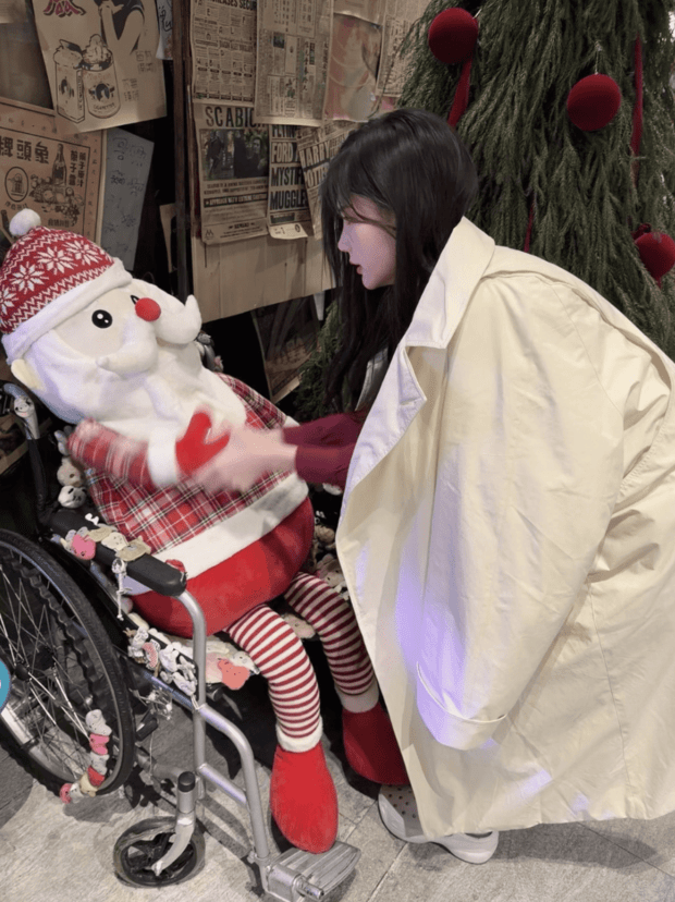 李一桐俯身轻触玩偶，姿态温柔舒展。