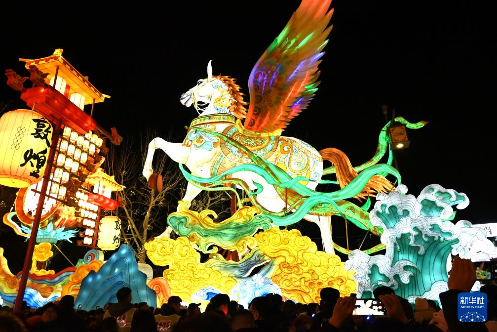 12月31日，游客在甘肃敦煌夜市举办的敦煌灯会上欣赏花灯。