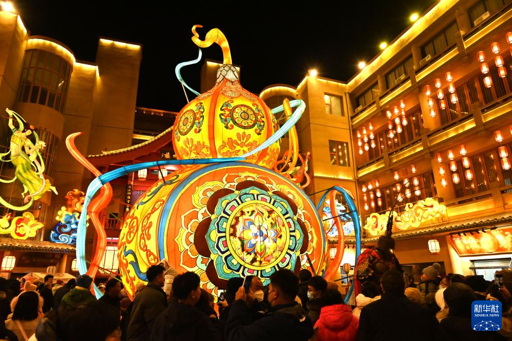12月31日，游客在甘肃敦煌夜市举办的敦煌灯会上欣赏花灯。