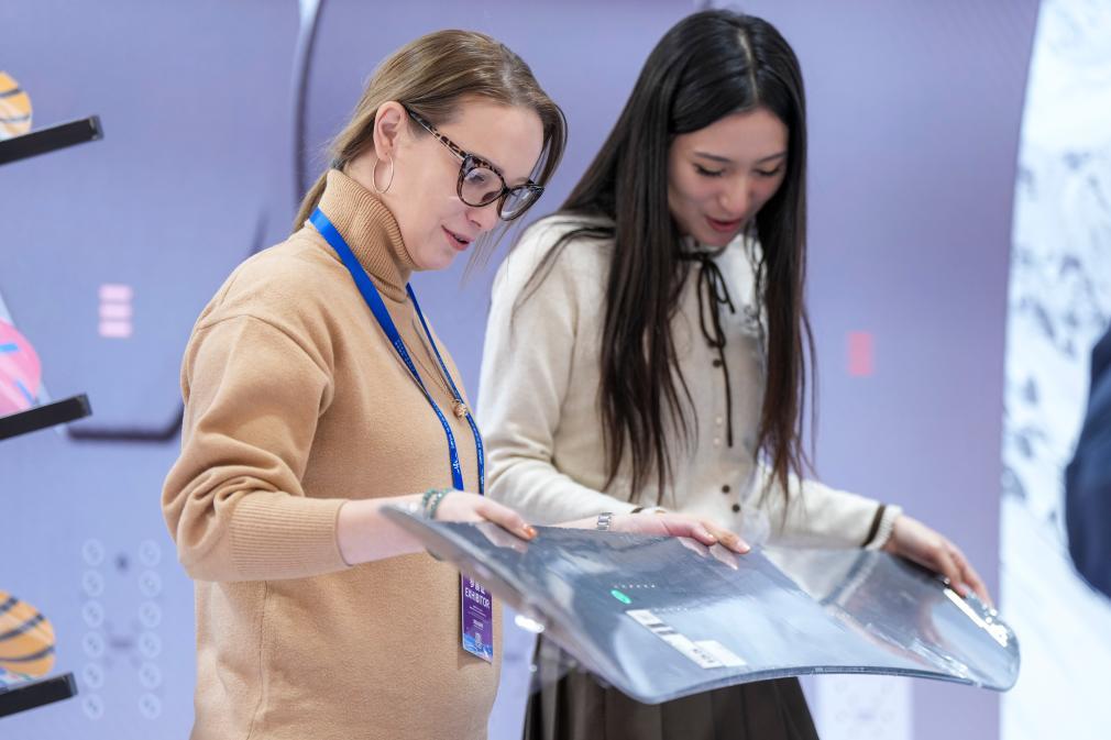 1月6日,在2026哈尔滨国际冰雪经济博览会展会现场,参会嘉宾(左)为参观者介绍智能碳纤维滑雪板性能。 新华社记者 王松 摄