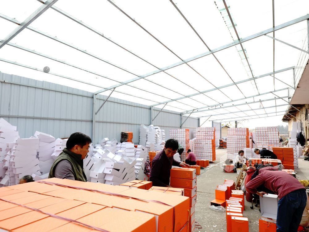 村民在家门口有序制作鞋子包装盒。