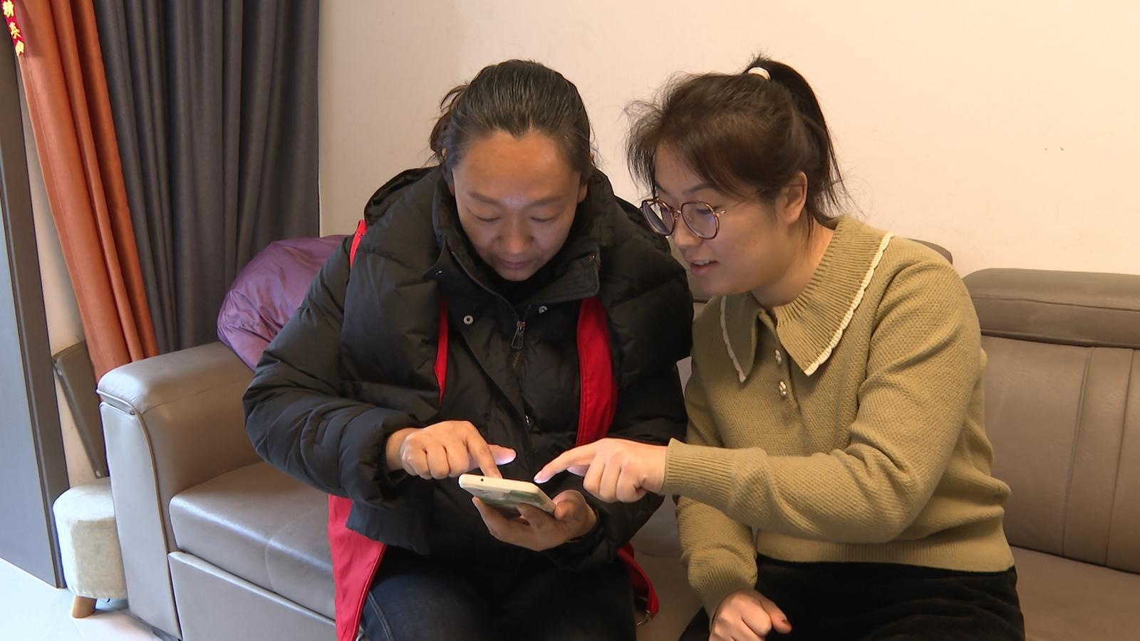 △居民许向洁为社区工作人员展示已领补贴记录