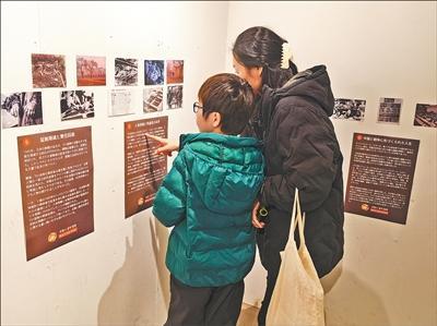 图片展上,一名当地女性向自己的孩子讲解有关揭