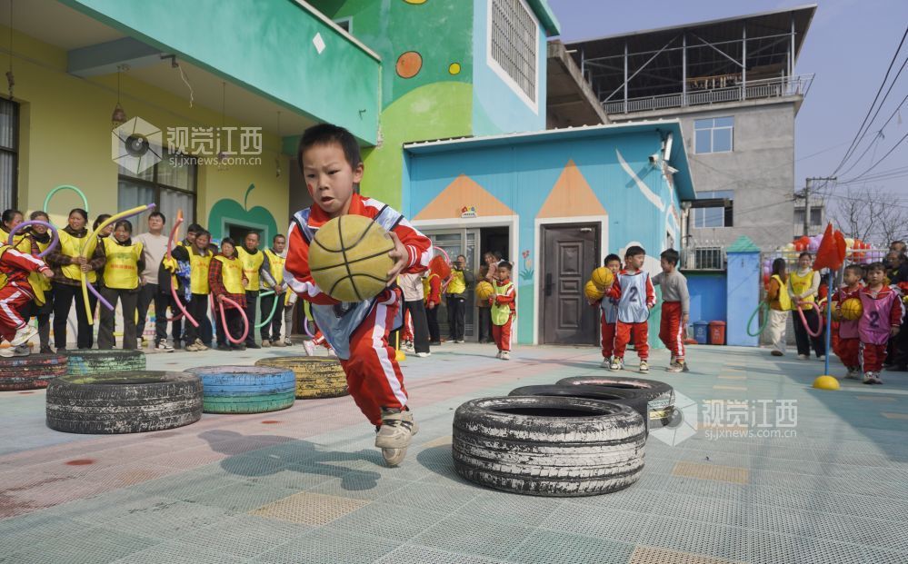 2026年1月4日，江西遂川县珠田镇育苗幼儿园里热闹非凡，一场亲子互动趣味运动会欢乐开启。萌娃们抱着篮球闯关卡：推轮胎、过木梯、翻垫子，动作利落又可爱；家长们手持彩圈助威，现场笑声与掌声交织。