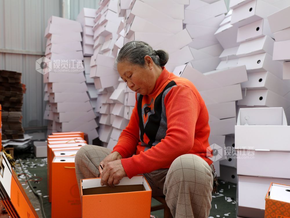 村民在家门口有序制作鞋子包装盒。