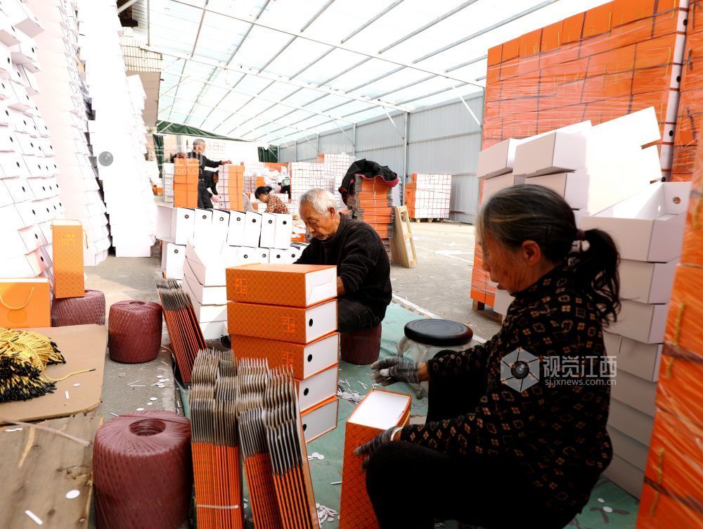 村民在家门口有序制作鞋子包装盒。