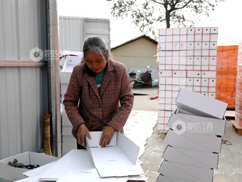 村民在家门口有序制作鞋子包装盒。