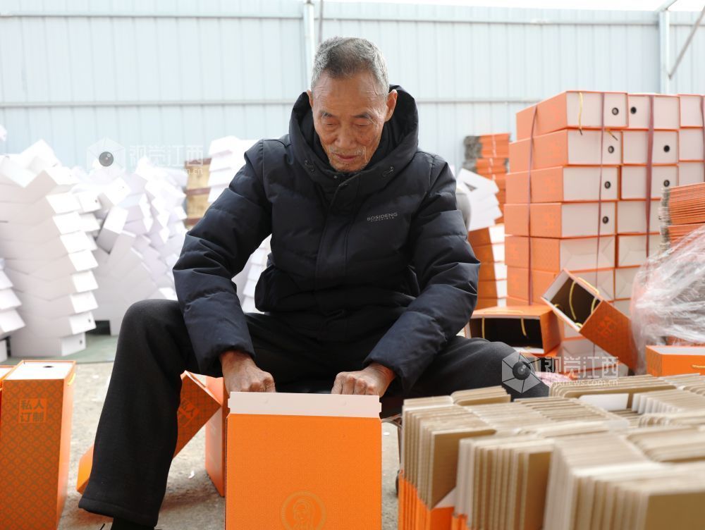 村民在家门口有序制作鞋子包装盒。