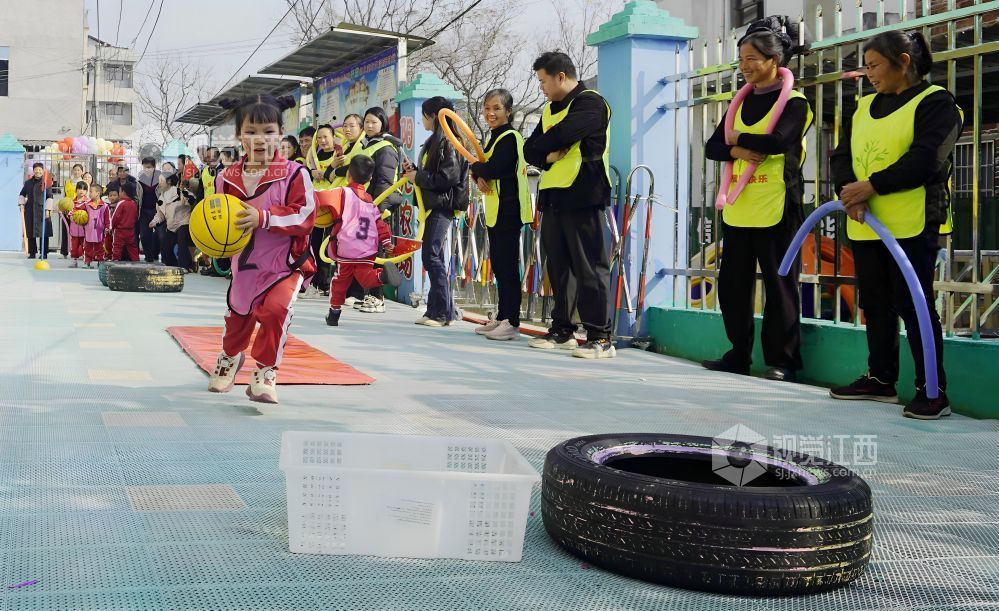 2026年1月4日，江西遂川县珠田镇育苗幼儿园里热闹非凡，一场亲子互动趣味运动会欢乐开启。萌娃们抱着篮球闯关卡：推轮胎、过木梯、翻垫子，动作利落又可爱；家长们手持彩圈助威，现场笑声与掌声交织。