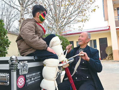 杨民杰在给小演员传授高跷绑扎技巧。