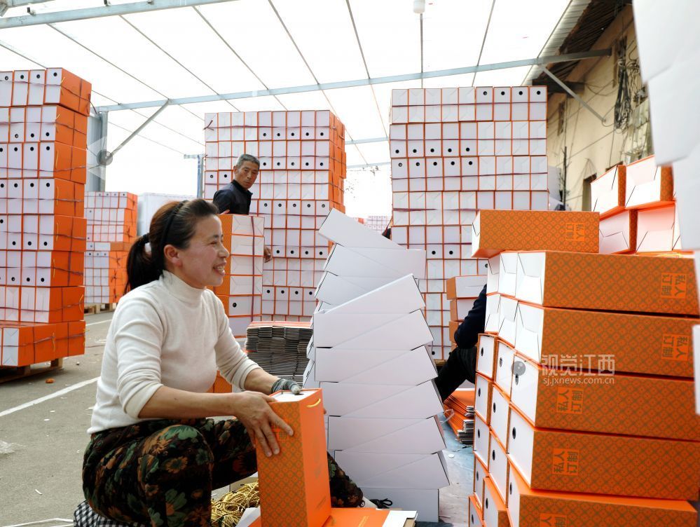 村民在家门口有序制作鞋子包装盒。