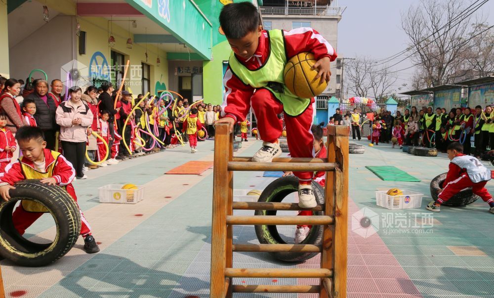 2026年1月4日，江西遂川县珠田镇育苗幼儿园里热闹非凡，一场亲子互动趣味运动会欢乐开启。萌娃们抱着篮球闯关卡：推轮胎、过木梯、翻垫子，动作利落又可爱；家长们手持彩圈助威，现场笑声与掌声交织。