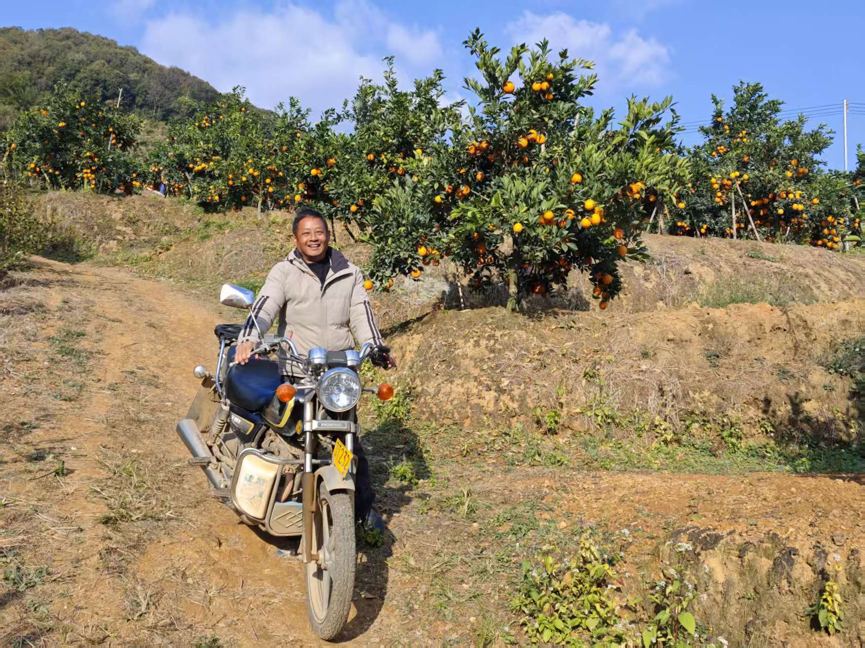 王学义骑着摩托车在果园