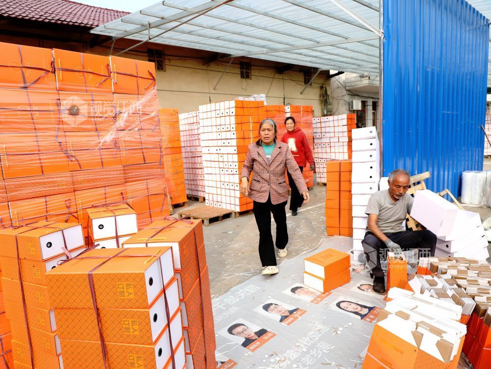 村民在家门口有序制作鞋子包装盒。