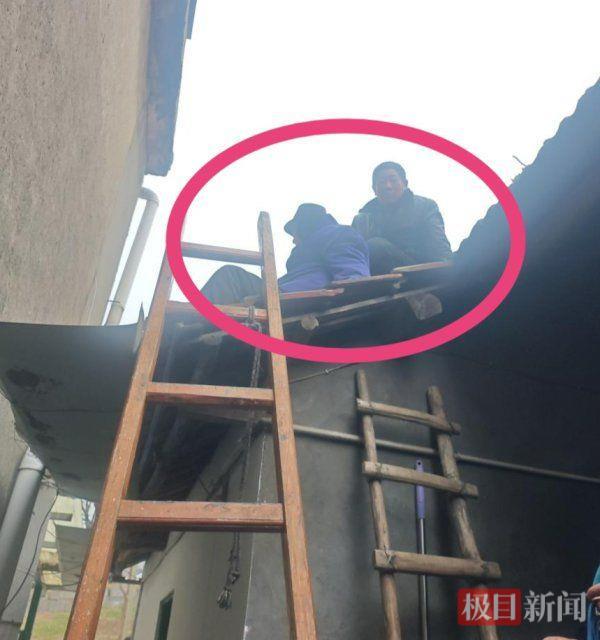 张大爷（左）的邻居在屋顶陪张大爷等待救援人员到来。 （极目新闻通讯员 夏明桐 摄）