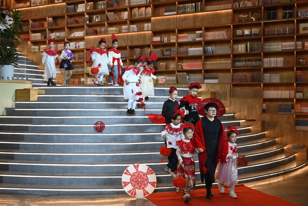 1月11日，敦煌剪纸非遗传承人庄生娟（前中）与小朋友们一同展示剪纸服饰作品。新华社发（张晓亮　摄）