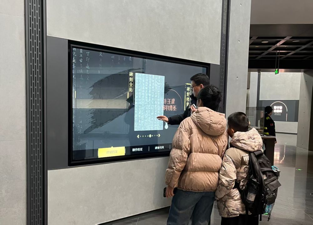 互动屏幕前,游客们正聚精会神观看碑帖。(受访者供图)