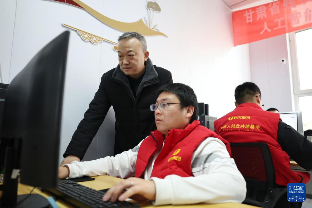 在兰州市心连心社会工作服务中心残疾人就业工坊,社会工作者王生番(左)指导残疾人AI训练师进行数据标注工作(1月14日摄)。新华社记者 陈斌 摄