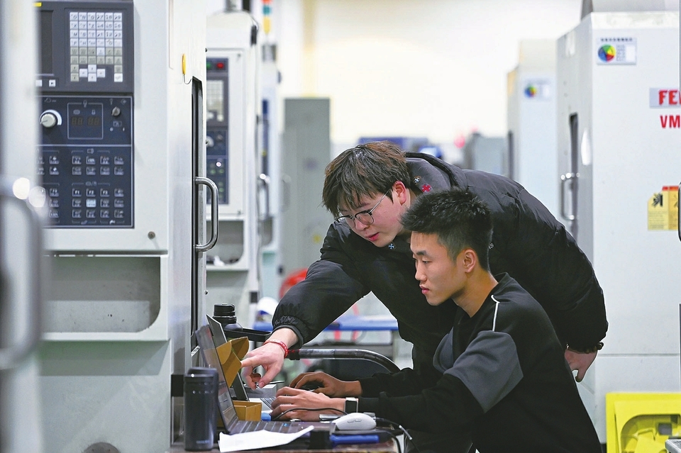 2025赛季冠军队成员郝艳鑫（左）指导新赛季成员梁凯斐进行CNC铝件加工。