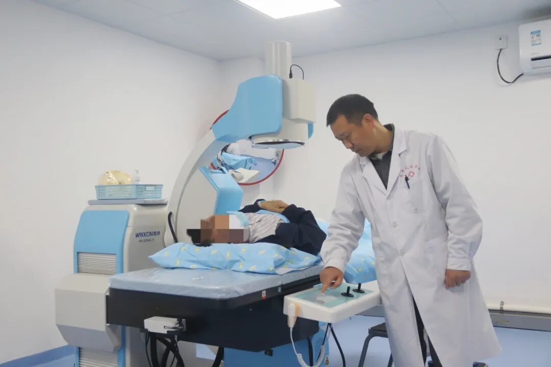 图：碎石科治疗室内，乐平医院医生正在询问患者情况和查看设备状态