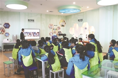 课堂上，科技馆老师正带领学生们观察植物标本，并指导大家学习标本分类的方法。