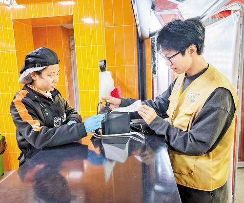 2025年12月19日，李立宇（右）正在无声餐厅内为听障员工调试外卖来单声光提醒系统。 燕赵都市报记者 李淑丽摄