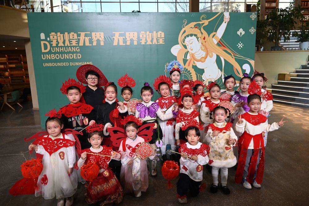 1月11日，敦煌剪纸非遗传承人庄生娟（后排左二）与身着剪纸服饰作品的小朋友们合影留念。新华社发（张晓亮　摄）