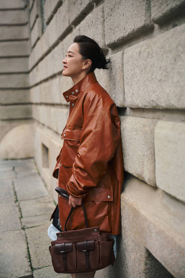 贾玲穿棕皮衣靠墙，侧颜状态松弛又自在。