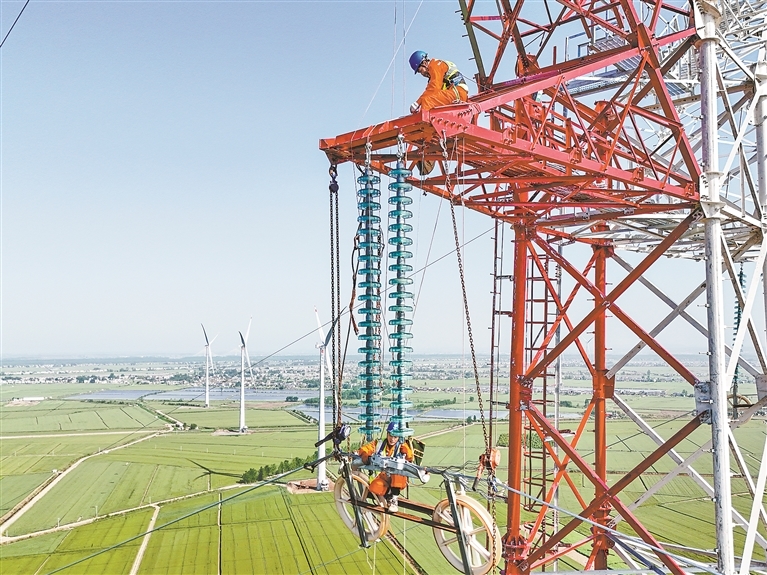 2025年4月18日,在彭泽县棉船风电项目110千伏配套线路施工现场,工作人员登上172.8米高的铁塔架设导线。江西日报全媒体记者 洪子波摄