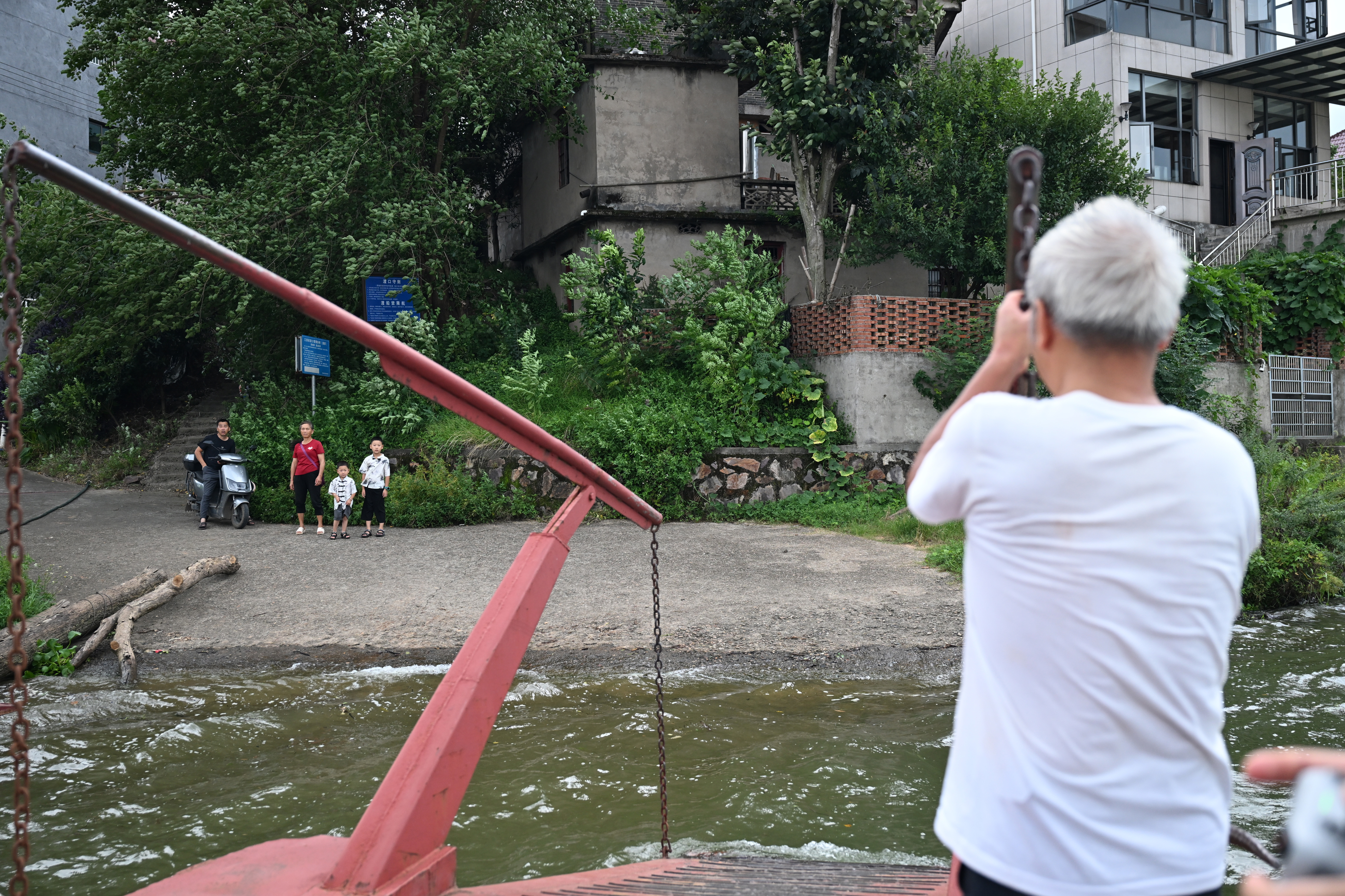 ▲2025年7月30日,在泰和县永昌渡口,老渡工汤正荣在渡船上帮忙。