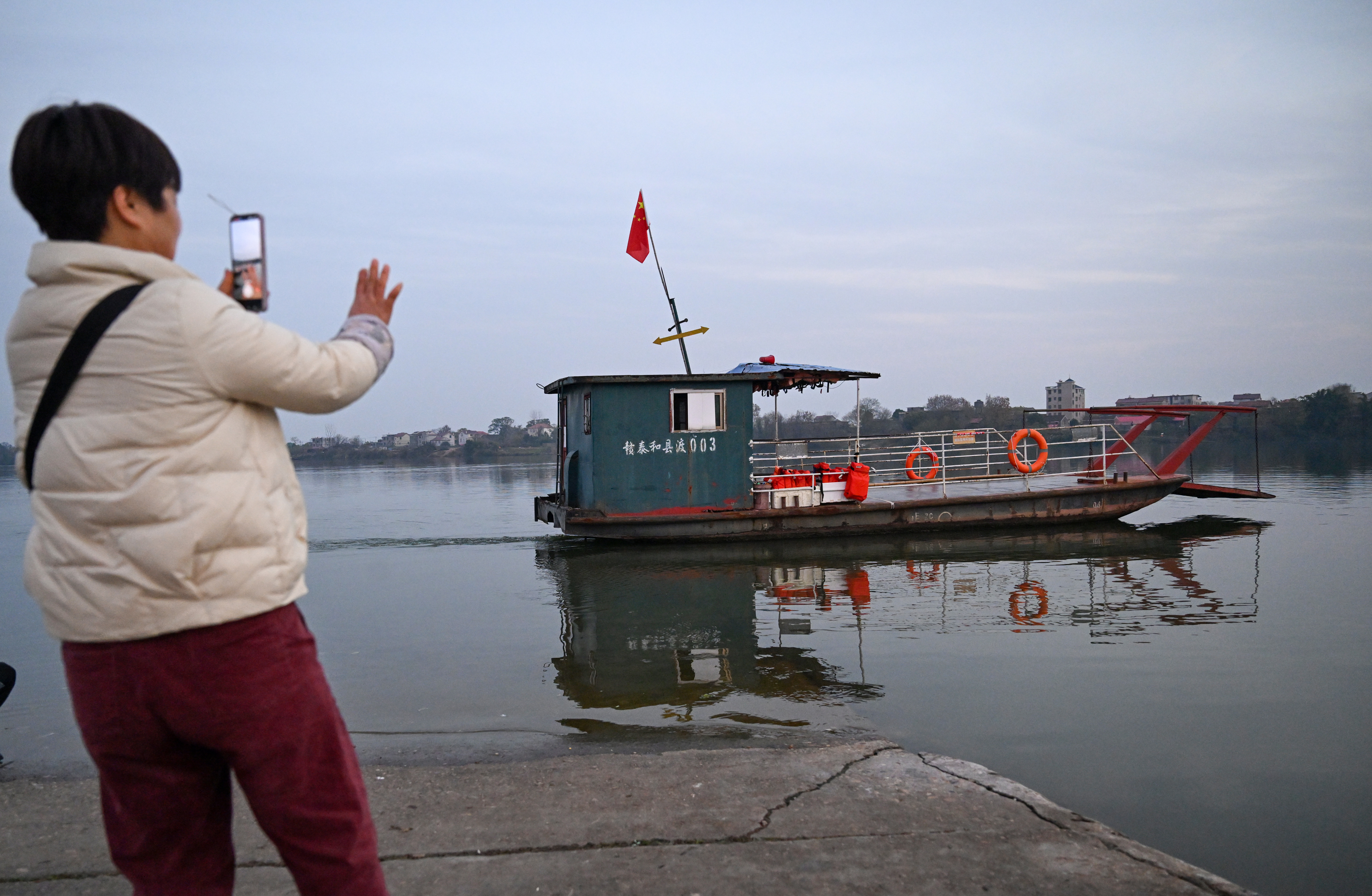 ▲2025年12月30日傍晚,泰和永昌渡口,市民挥手送别最后一班渡船。