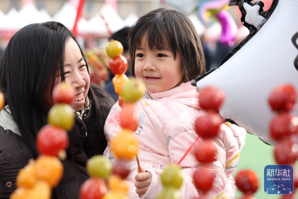 家长和孩子在年货大集上挑选糖葫芦(1月19日摄) 新华社记者 陈斌 摄