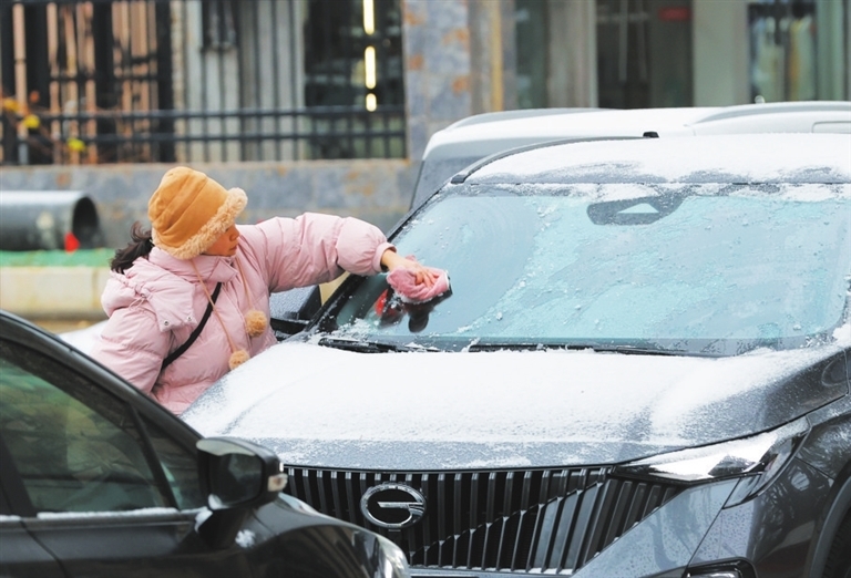 市民清理车上积雪。（浔阳晚报记者 刘家 摄）