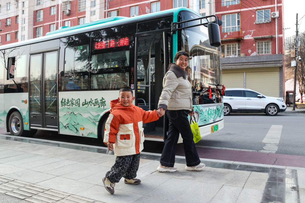 1月17日,在甘肃省陇南市两当县,祖孙二人乘坐免费公交到站后手牵手回家。新华社记者 郎兵兵 摄