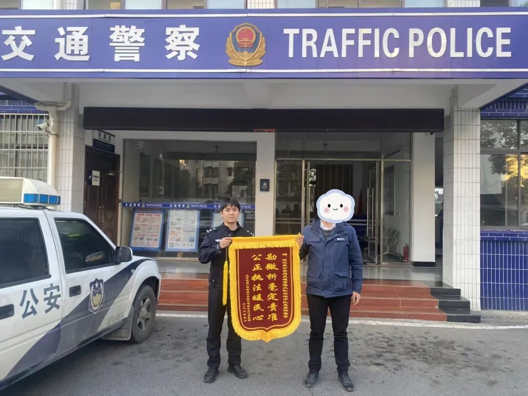 ▲锦旗由保险公司理赔员代表公司及陈女士，送至水边中队办案民警手中。