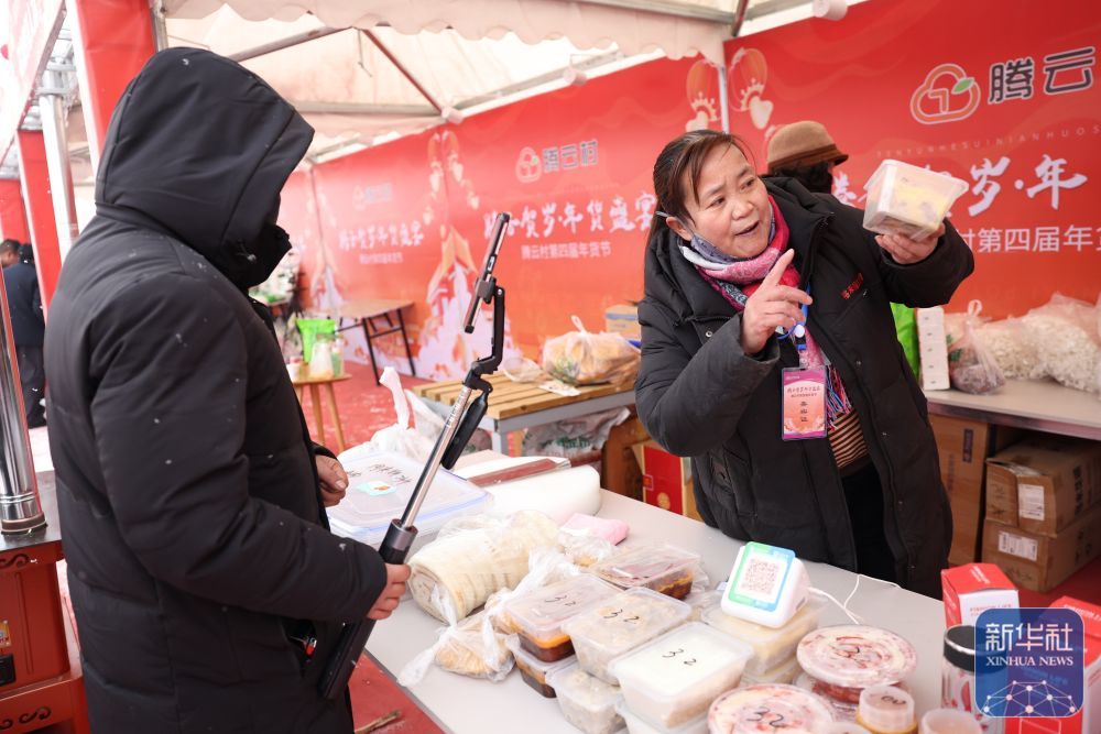 一位摊主在年货大集上对着手机镜头直播自家的特色美食(1月19日摄) 新华社记者 陈斌 摄