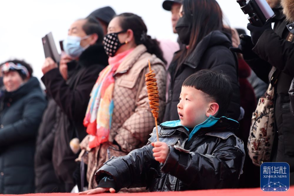 一位小朋友在年货大集上边吃美食边看演出(1月19日摄) 新华社记者 陈斌 摄