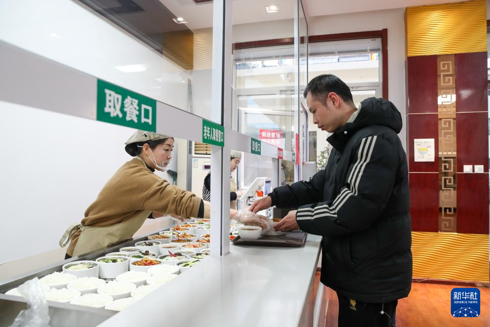 1月17日,一名男士在甘肃省陇南市两当县的两当宾馆共享食堂窗口前取餐。新华社记者 郎兵兵 摄