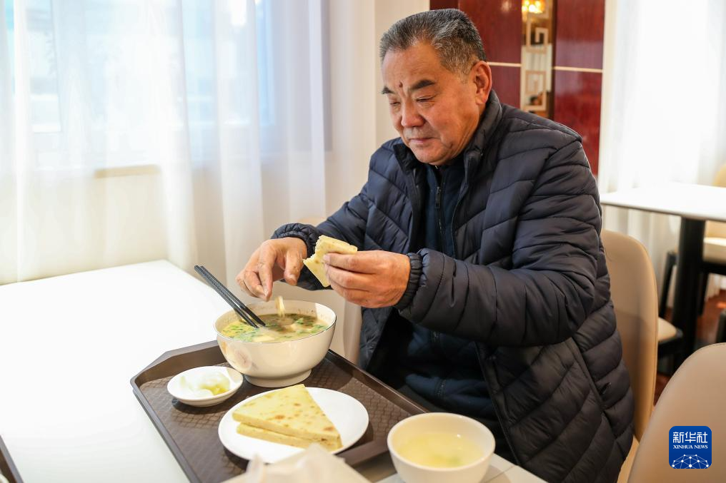 1月17日,一名老人在甘肃省陇南市两当县的两当宾馆共享食堂内吃泡馍。新华社记者 郎兵兵 摄
