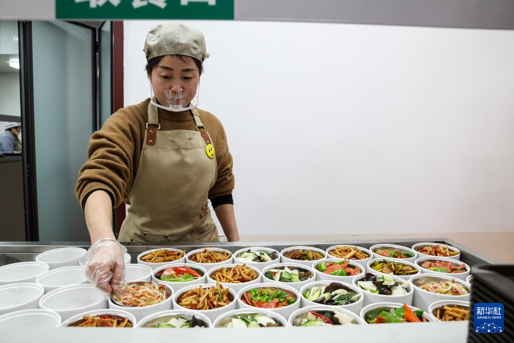 1月17日,在甘肃省陇南市两当县的两当宾馆共享食堂内,工作人员整理加热台上的菜品。新华社记者 郎兵兵 摄