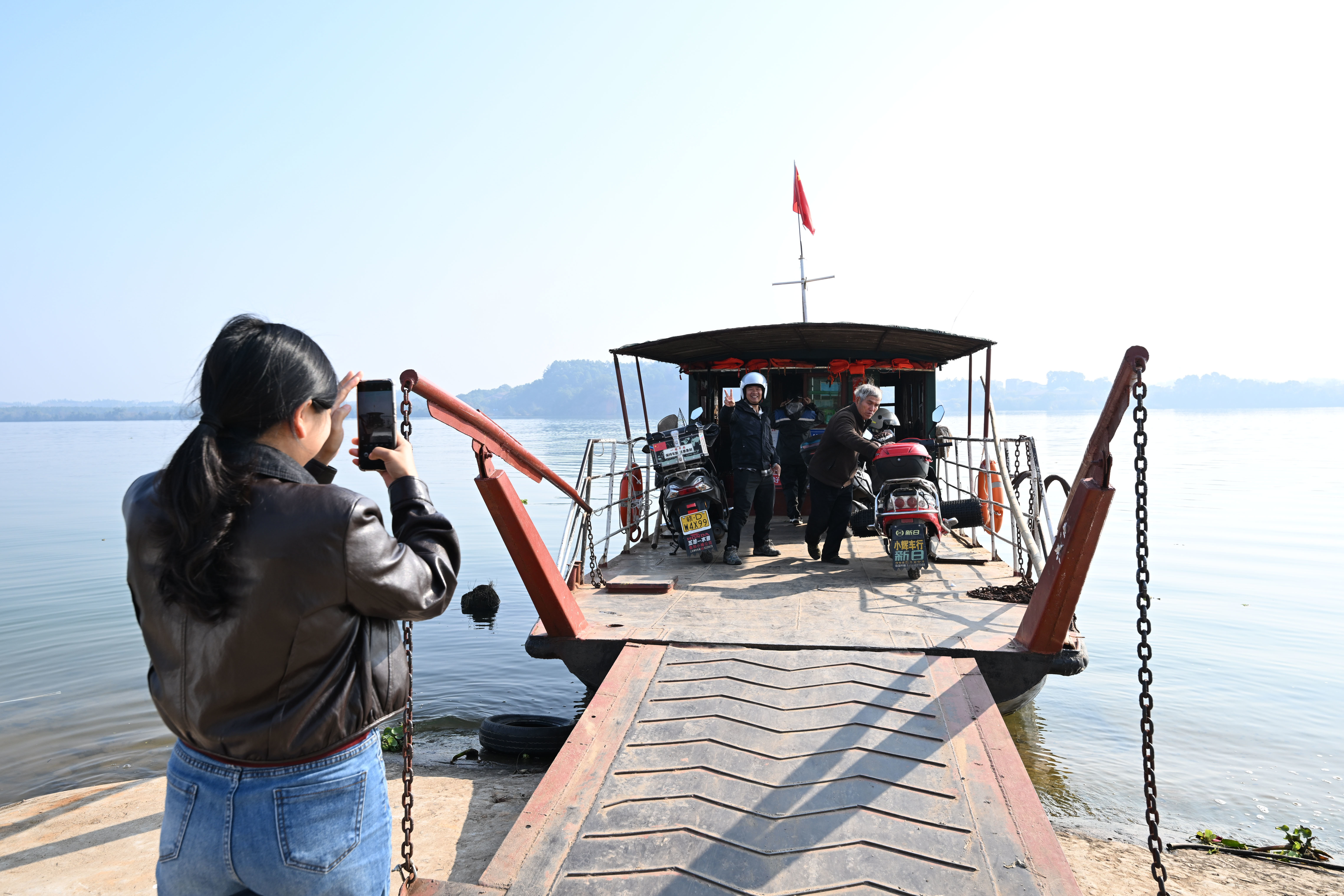 ▲12月30日,村民许超(左二)赶来竹山渡口,登上最后一天渡运的渡船拍照。