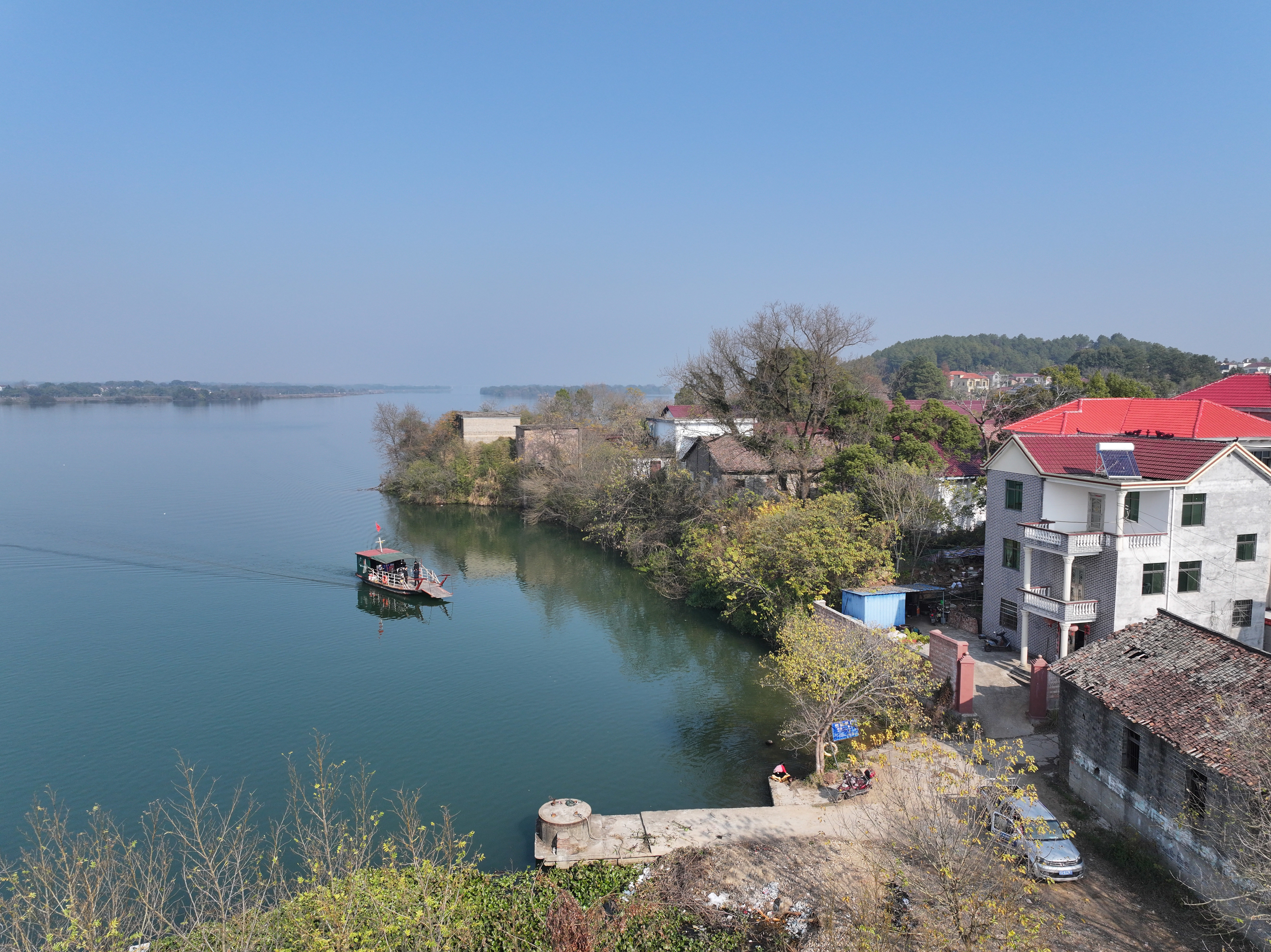 ▲泰和竹山渡口,渡工曾健龙驾驶渡船驶向万合镇竹山村。画面右边这栋三层新房便是曾健龙的家。