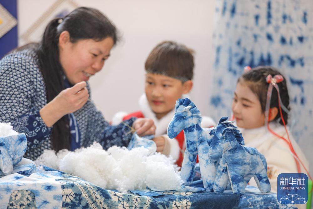 1月16日,在山东省青岛市李沧区夏庄路幼儿园,小朋友跟着老师学习缝制扎染马。新华社发(张鹰 摄)