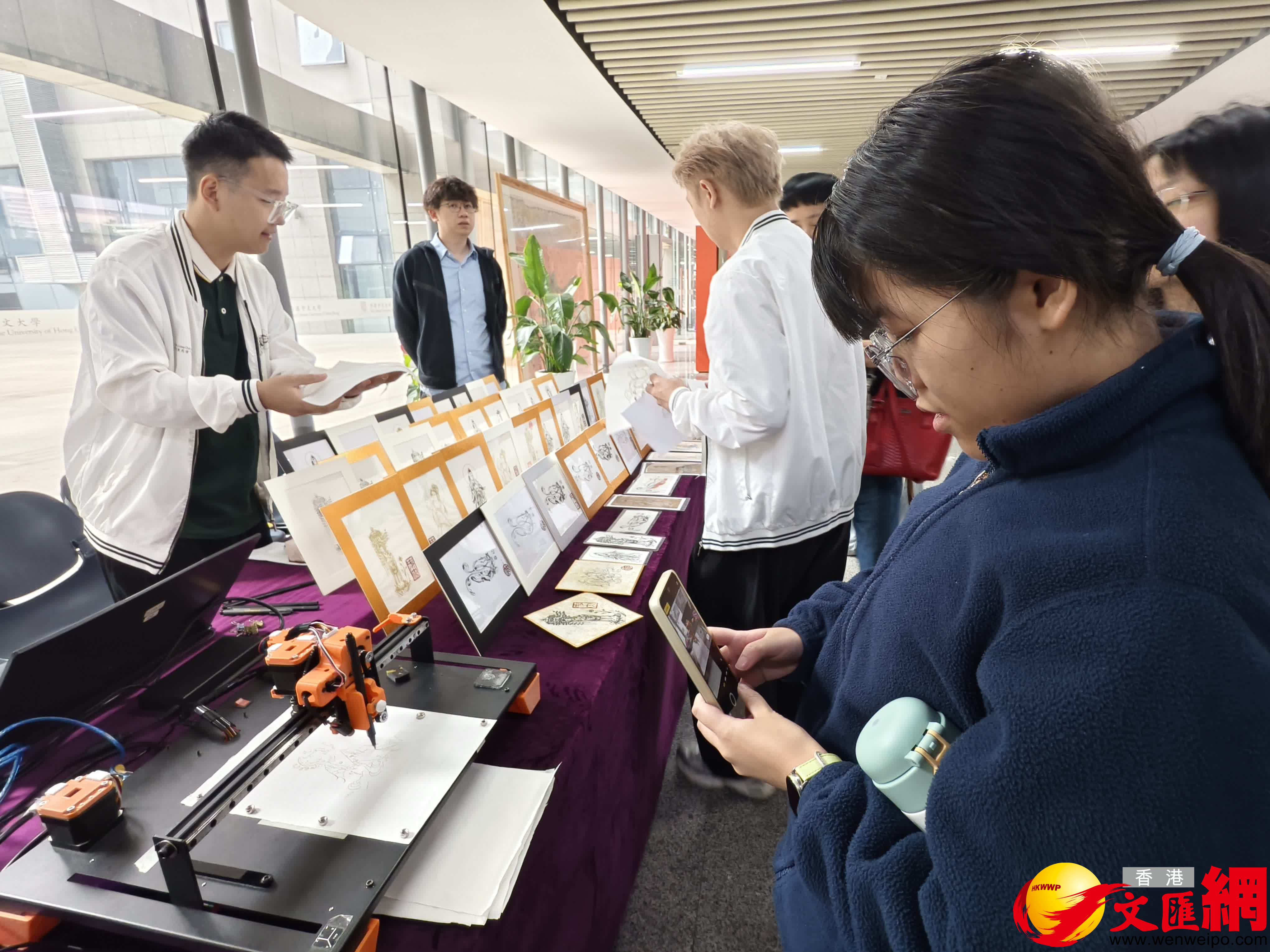 在這些美輪美奐的作品旁邊，還有一台「繪畫」機器人，正一筆一划地以線條畫的形式「臨摹」出畫家張傑龍的敦煌畫作，吸引了參展觀眾們駐足。記者　胡永愛攝