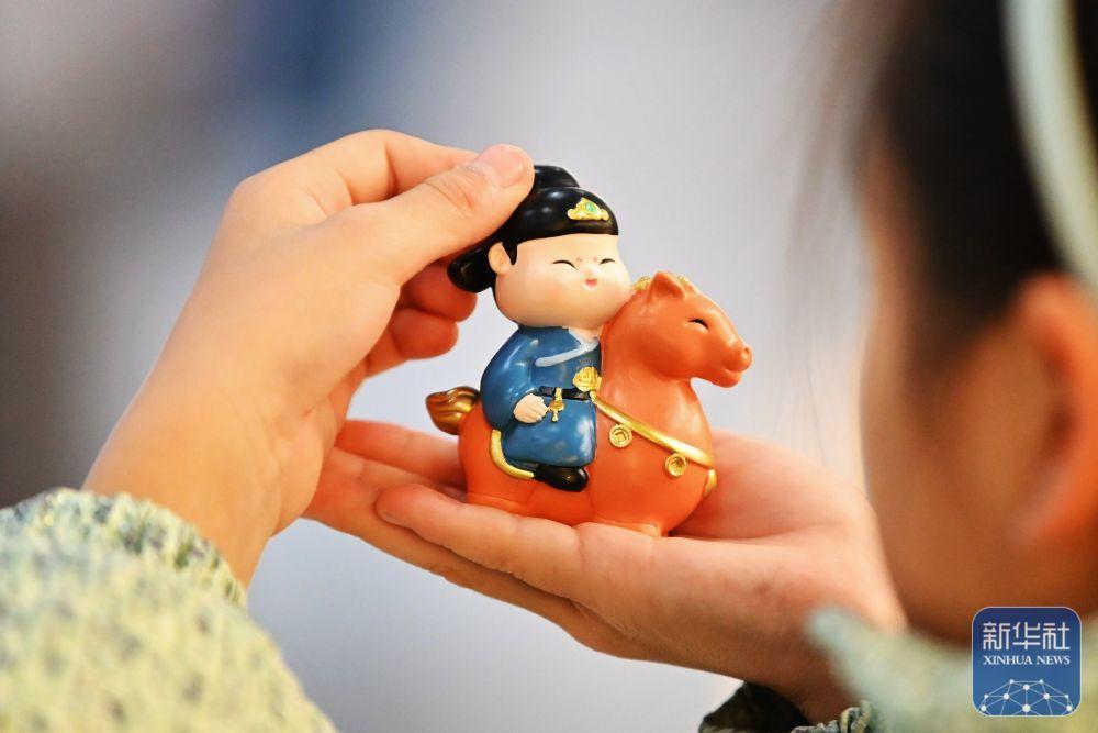 1月17日,在山东滕州博物馆文创商店,一名小朋友选购“踏马游春”文创摆件。新华社发(李志军 摄)