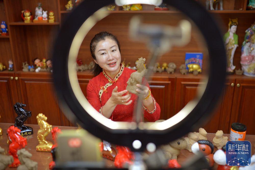 1月21日,在山东省青岛市城阳区河套街道汇海社区泥塑非遗工坊,刘梅铃通过网络直播销售。新华社发(王海滨 摄)