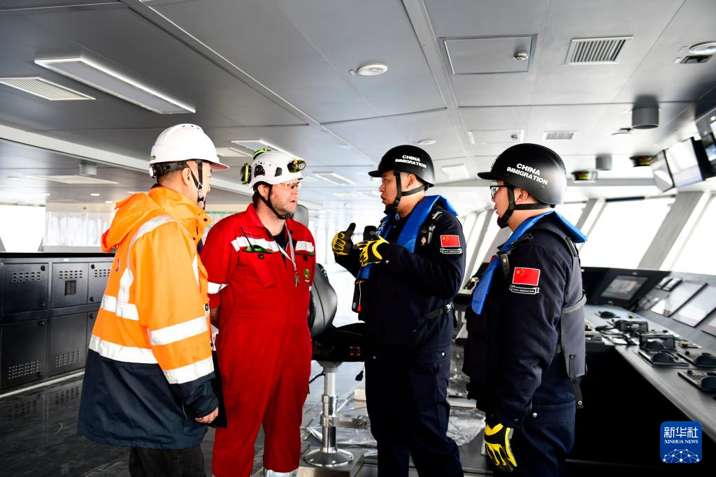 2月3日，在中集来福士山东烟台建造基地，山东出入境边防检查总站烟台边检站来福士警务室的民警对即将离港的比利时风电安装船进行船体检查，并与船员交流。新华社记者 郭绪雷 摄