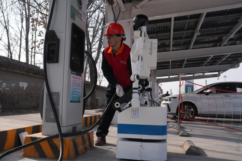 工作人员与机器人核对充电枪连接状态。（李琳 摄）